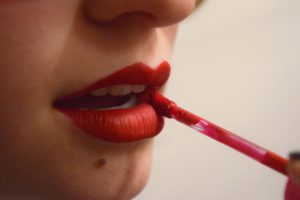 a woman applying lip polish