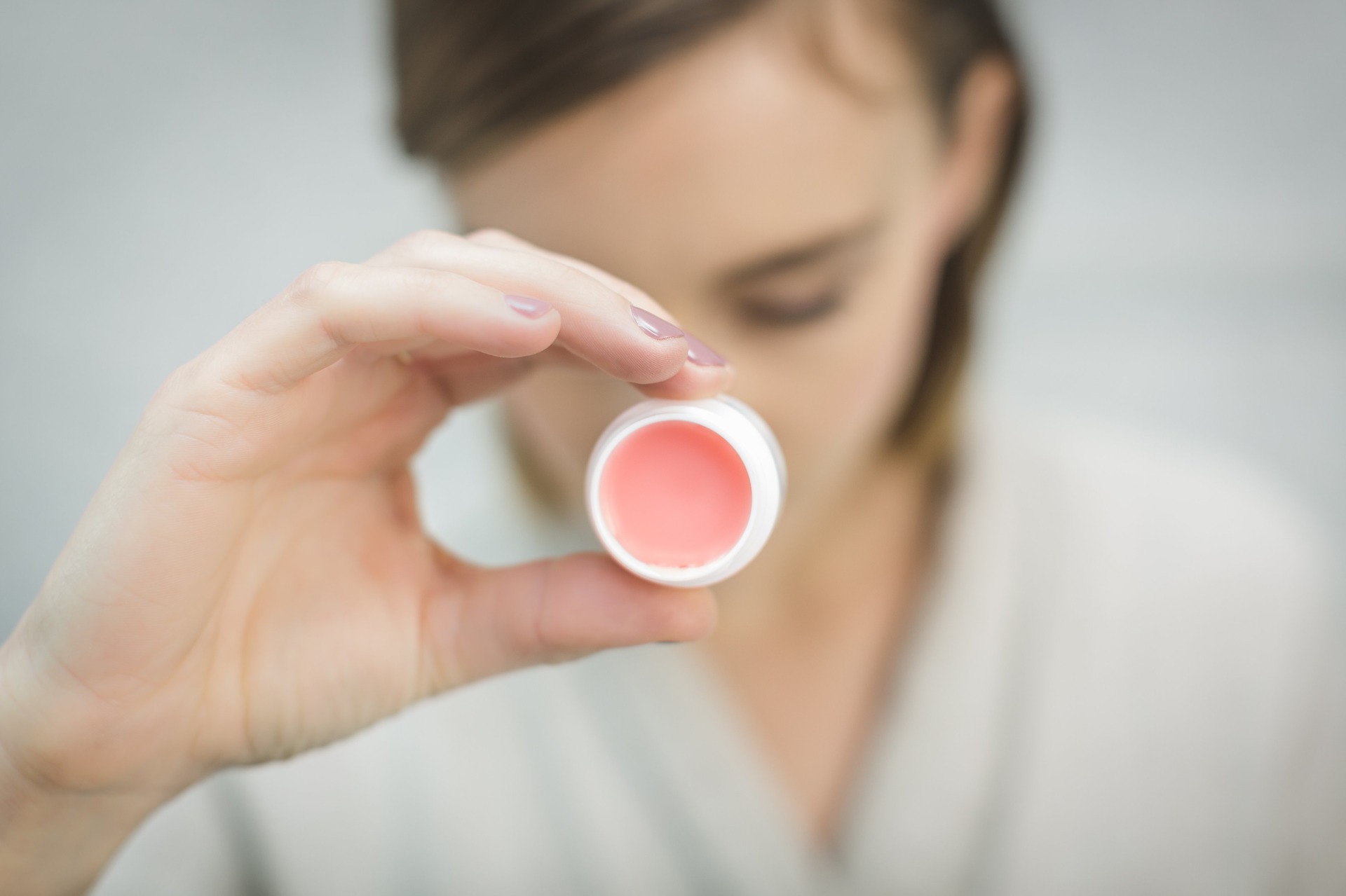 Girl is focusing a lip balm on the camera