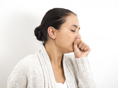 Woman holding her hand over her mouth while coughing