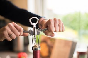 a person opening a wine bottle with a corkscrew