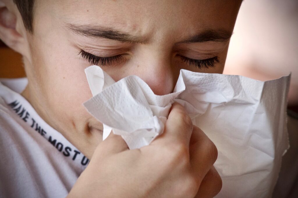 A boy holding a tissue to his nose